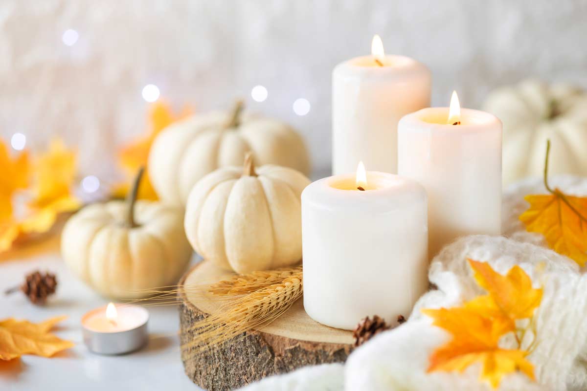 centrotavola autunnale con zucche e candele bianche appoggiate su una rondella di legno