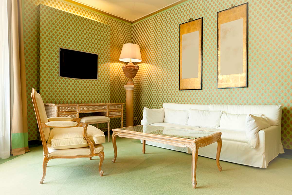 Salotto elegante con carta da parati geometrica verde e oro, tavolo in vetro con sedie vintage, luce naturale e dettagli di design contemporaneo