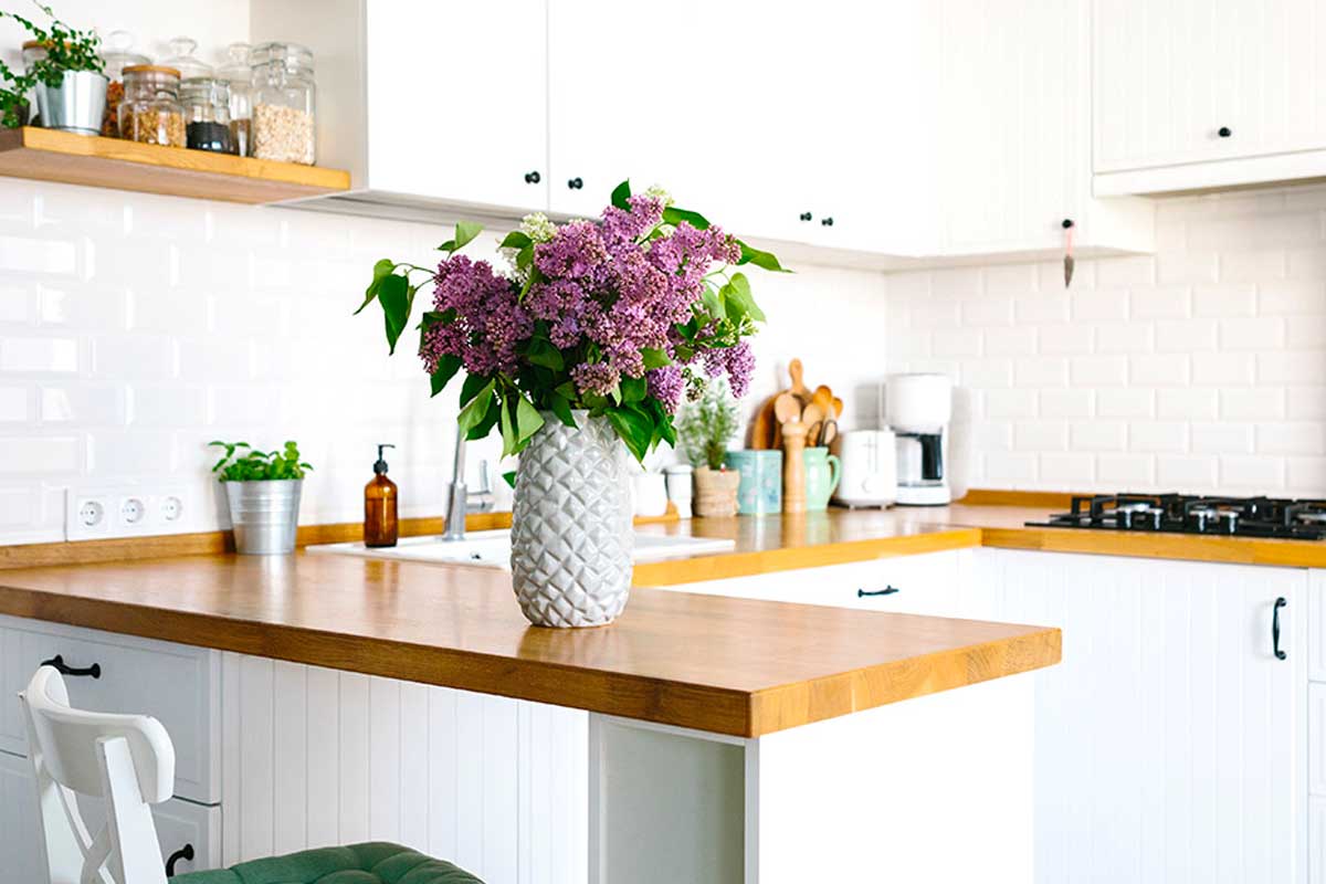 Cucina bianca con piccola penisola con top legno chiaro