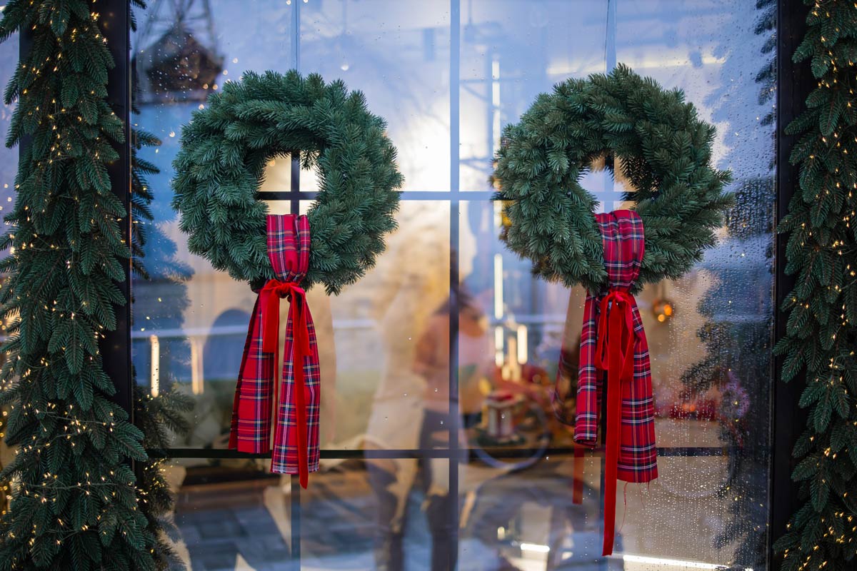 Due corone di rami di pino con fiocchi rossi sulla finestra lato esterno
