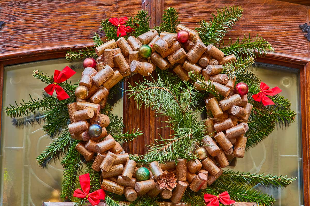 Corona rustica con tappi di sughero, pigne, fiocchi rossi e sempreverde