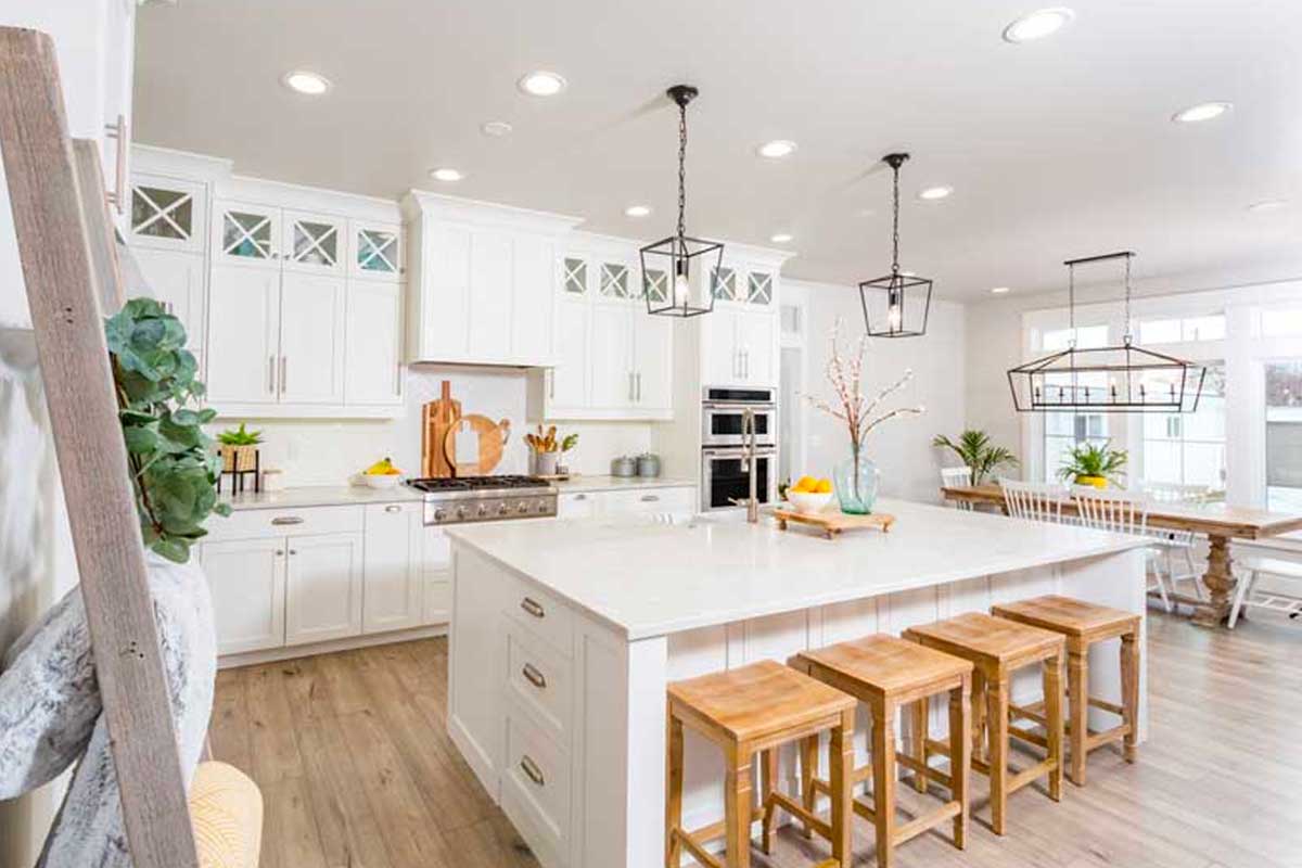 cucina bianca con isola e sgabelli legno chiaro