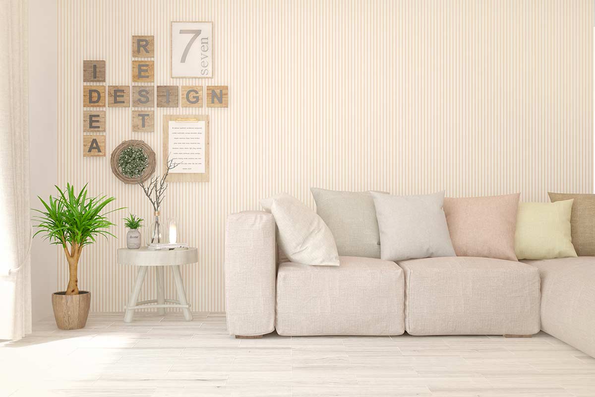 Salotto luminoso con divano beige, parete a righe sottili, cuscini pastello e decorazioni in legno naturale.