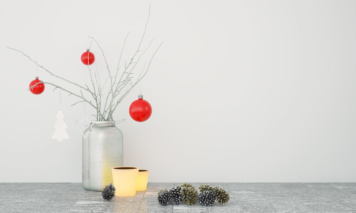 Barattolo di vetro con rami bianchi e palline rosse, decorazione natalizia minimal su tavolo chiaro. 