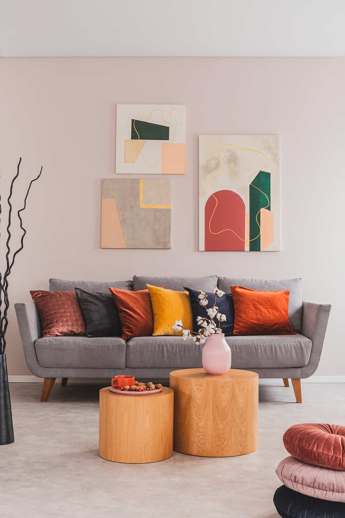 Salotto moderno con cuscini colorati e composizione di 3 quadri sopra al divano.