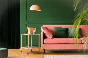 Divano rosa cipria con parete verde bosco.