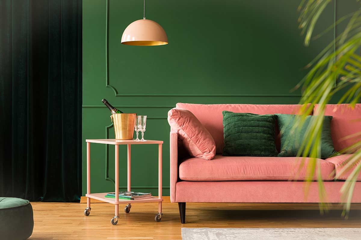 Divano rosa cipria con parete verde bosco.