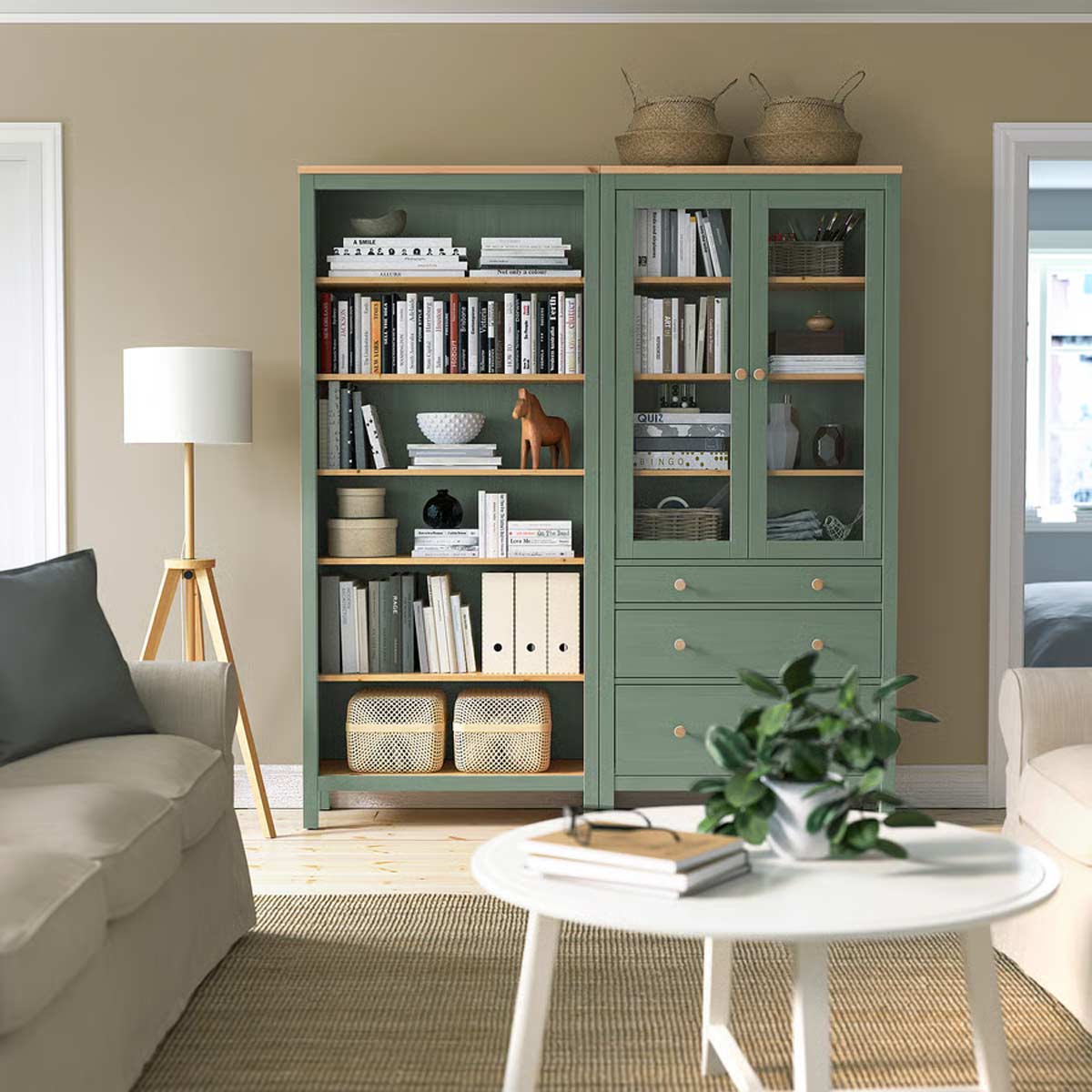 Parete attrezzata HEMNES IKEA verde salvia in salotto, con libreria, vetrina e cassetti, arredi naturali e luce morbida.