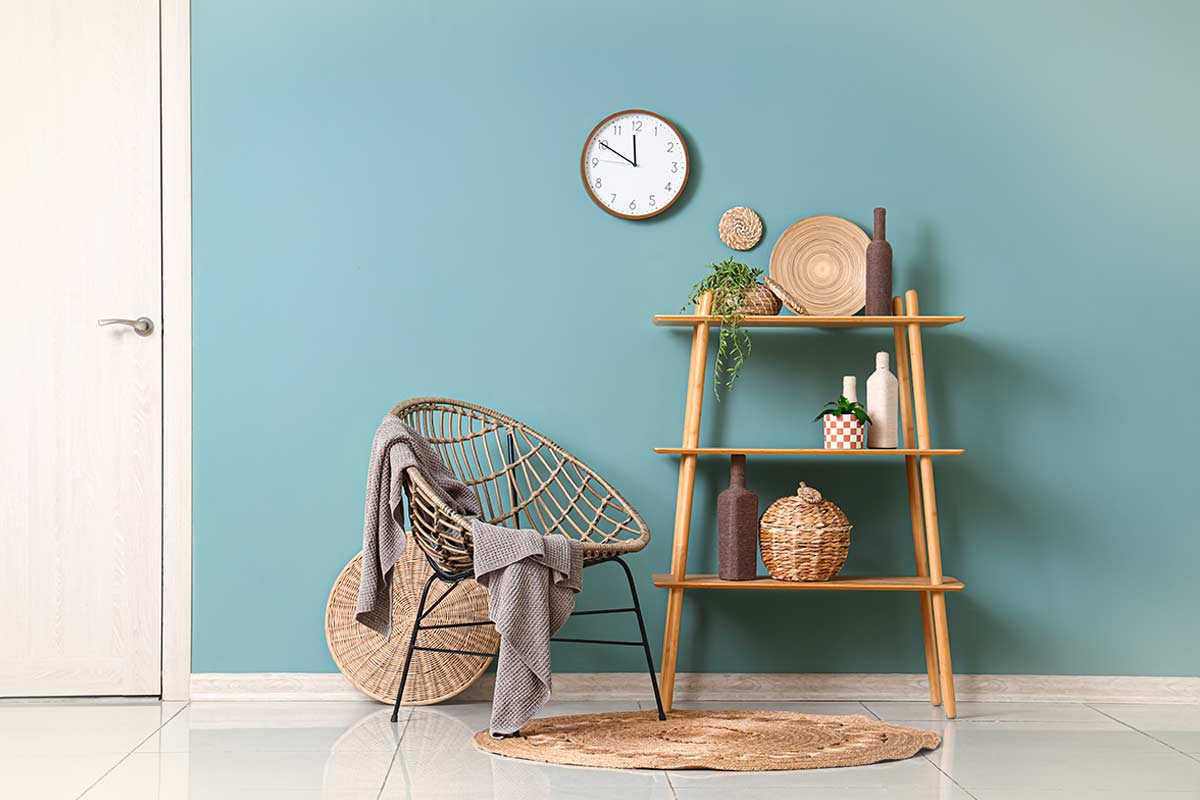 Mensole di design con oggetti in materiali naturali e composizione in gruppi da tre, su parete azzurra.