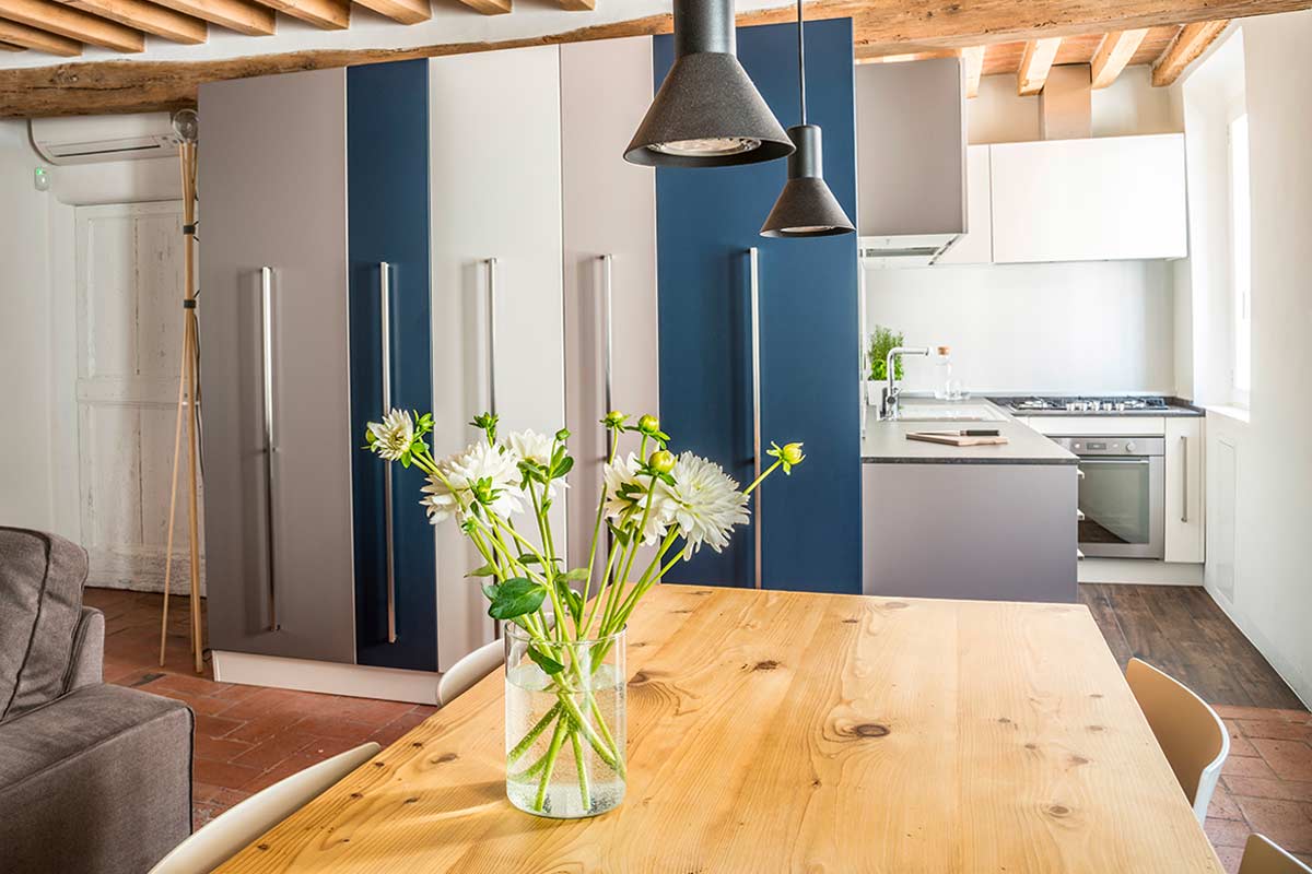 Esempio di open space moderno con cucina a vista, soffitto con travi in legno e mobili grigio-blu.