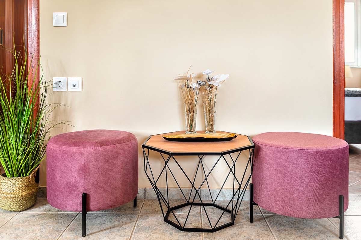 Pouf malva e tavolino geometrico in ingresso moderno con dettagli naturali.