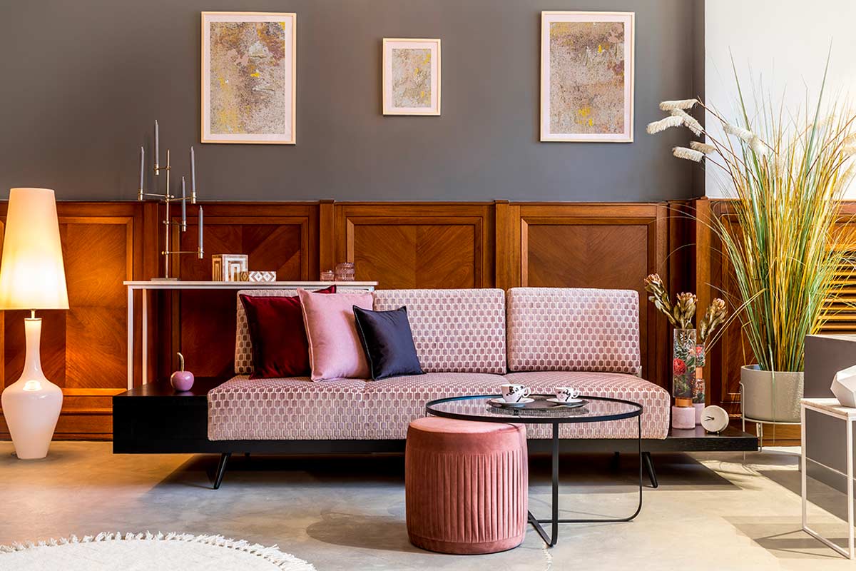 Soggiorno elegante con divano rosa. Dietro boiserie in legno. Foto © FollowTheFlow