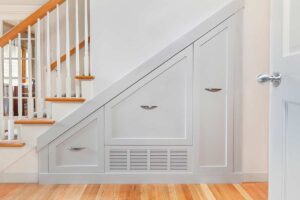 Armadi su misura sotto le scale in legno chiaro con ante integrate, soluzioni per dispensa o scarpiera in ambiente domestico moderno, foto: © Jo Ann Snover - Stock adobe