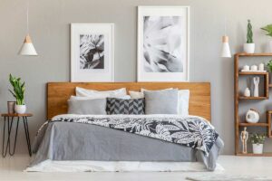 Camera moderna con letto in legno e quadri in bianco e nero come punto focale sopra la testata.