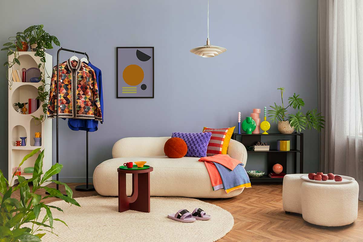 Soggiorno colorato con parete blu polvere chiaro, divano bianco e arredi eclettici su parquet.