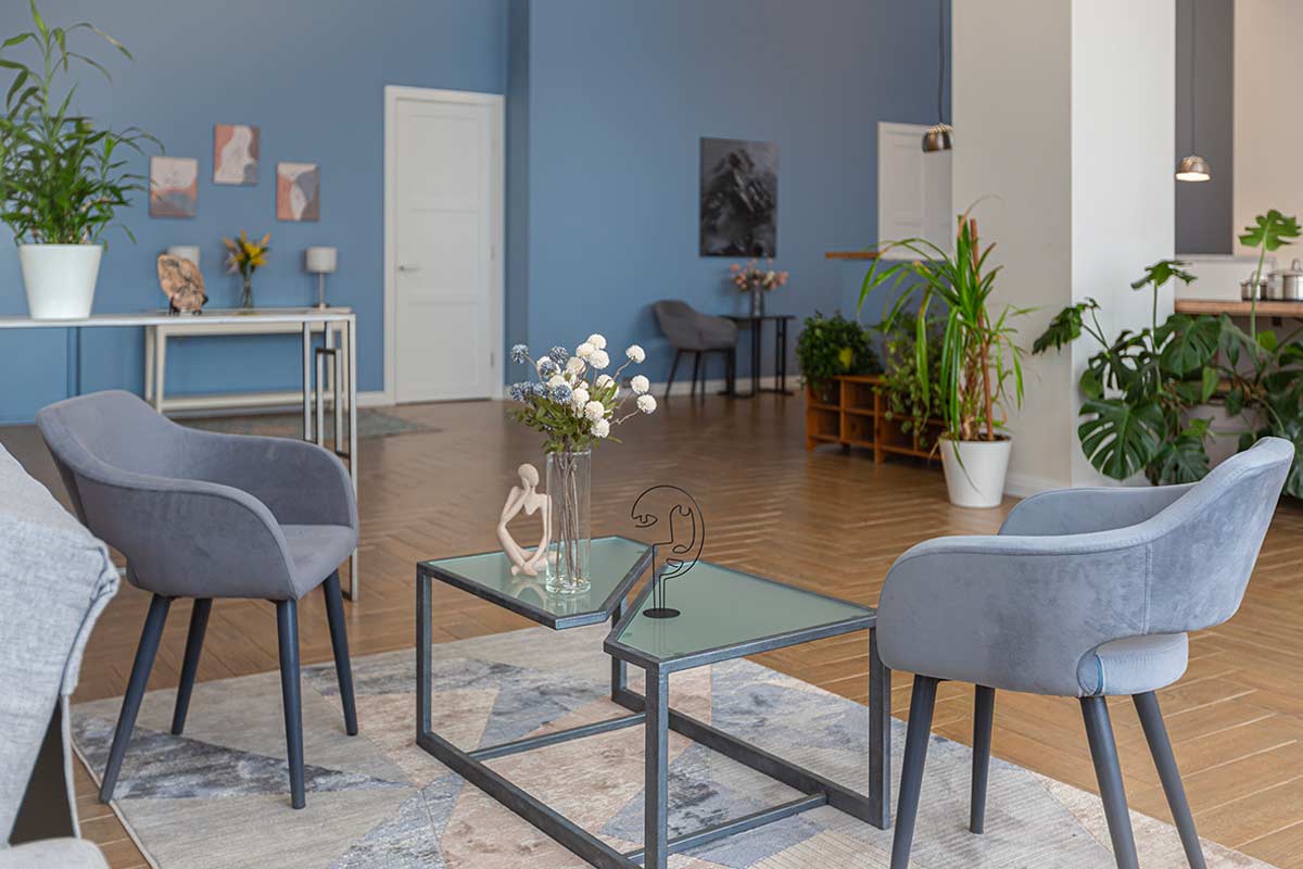 Salotto con pareti blu polvere, parquet in legno e arredi materici in stile moderno.