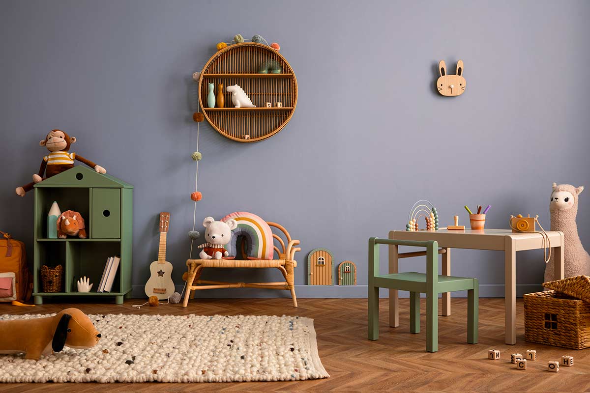 Cameretta per bambini con parete azzurro polvere, arredi in legno e verde salvia, giochi naturali e tappeto in lana, atmosfera accogliente e ordinata.