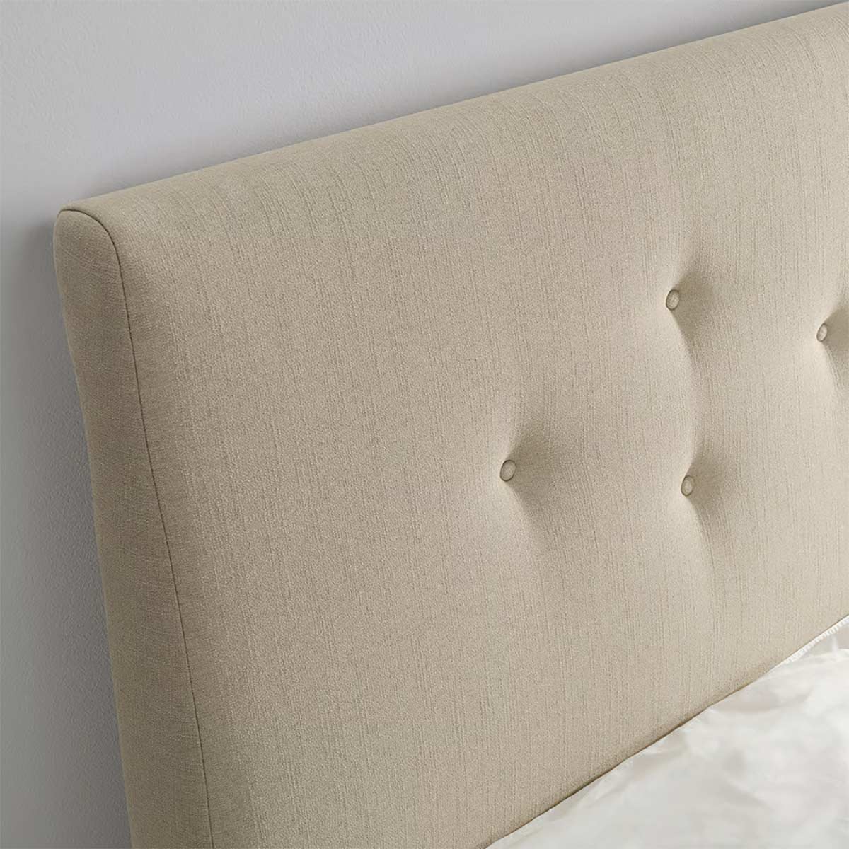 Dettaglio testiera letto IDANÄS in tessuto beige con bottoni decorativi e finitura effetto lino.