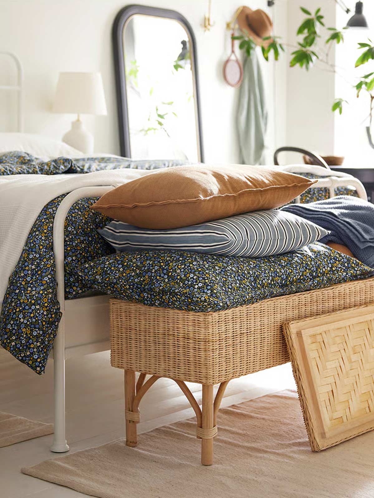 Camera da letto luminosa con panca contenitore IKEA TOLKNING in rattan posizionata ai piedi del letto.