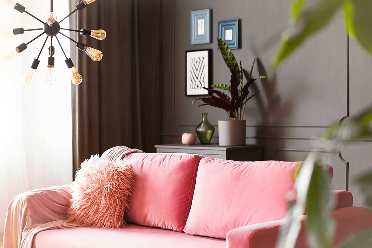 Divano rosa cipria su sfondo scuro: eleganza e profondità in salotto.