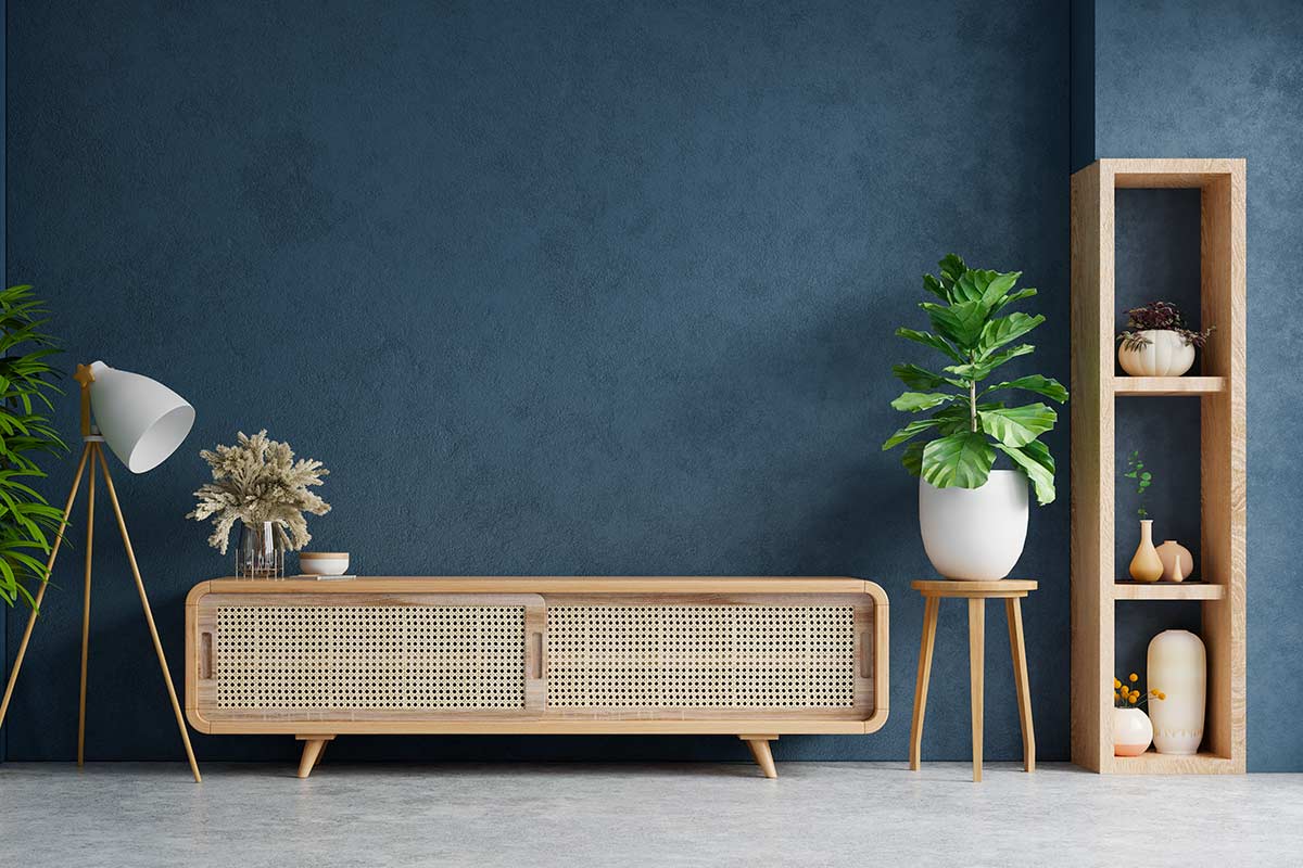 Soggiorno con parete blu scura e consolle legno chiaro.