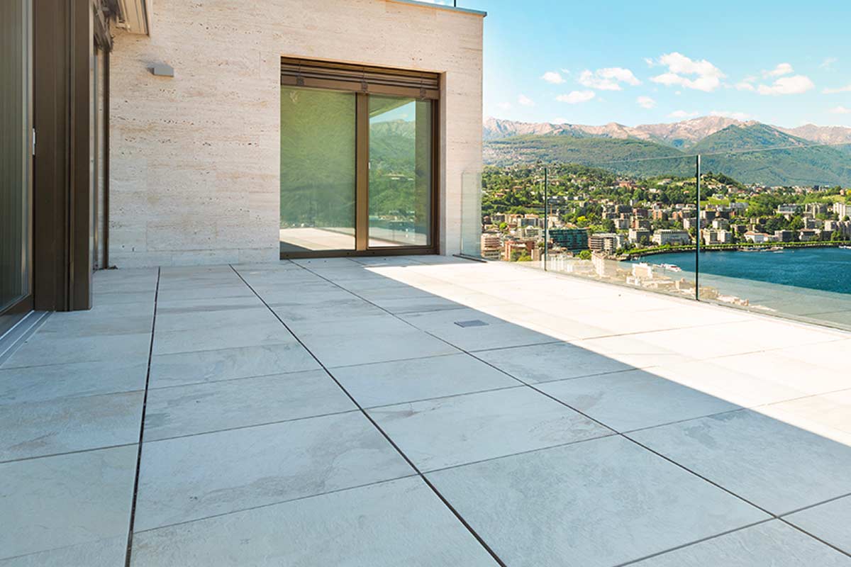 Terrazzo con pavimento in marmo bianco pulito, illuminato dal sole, esempio di superficie trattata senza candeggina con metodi naturali.