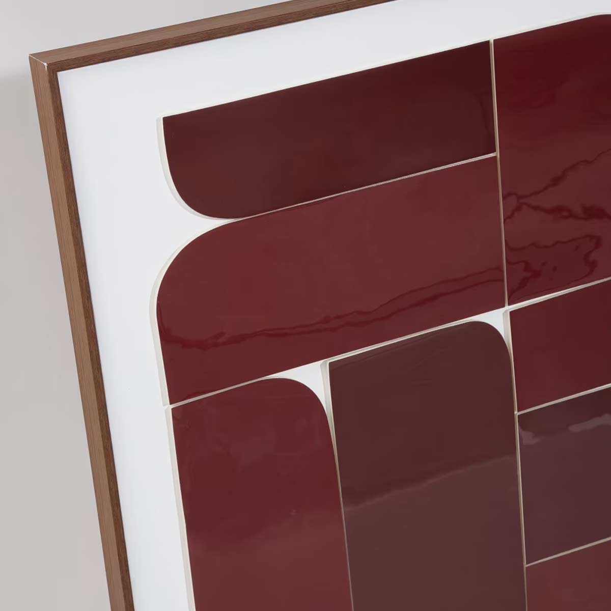 Dettaglio del quadro Amarante: superficie laccata rosso scuro con forme geometriche su fondo bianco e cornice sottile in legno.
