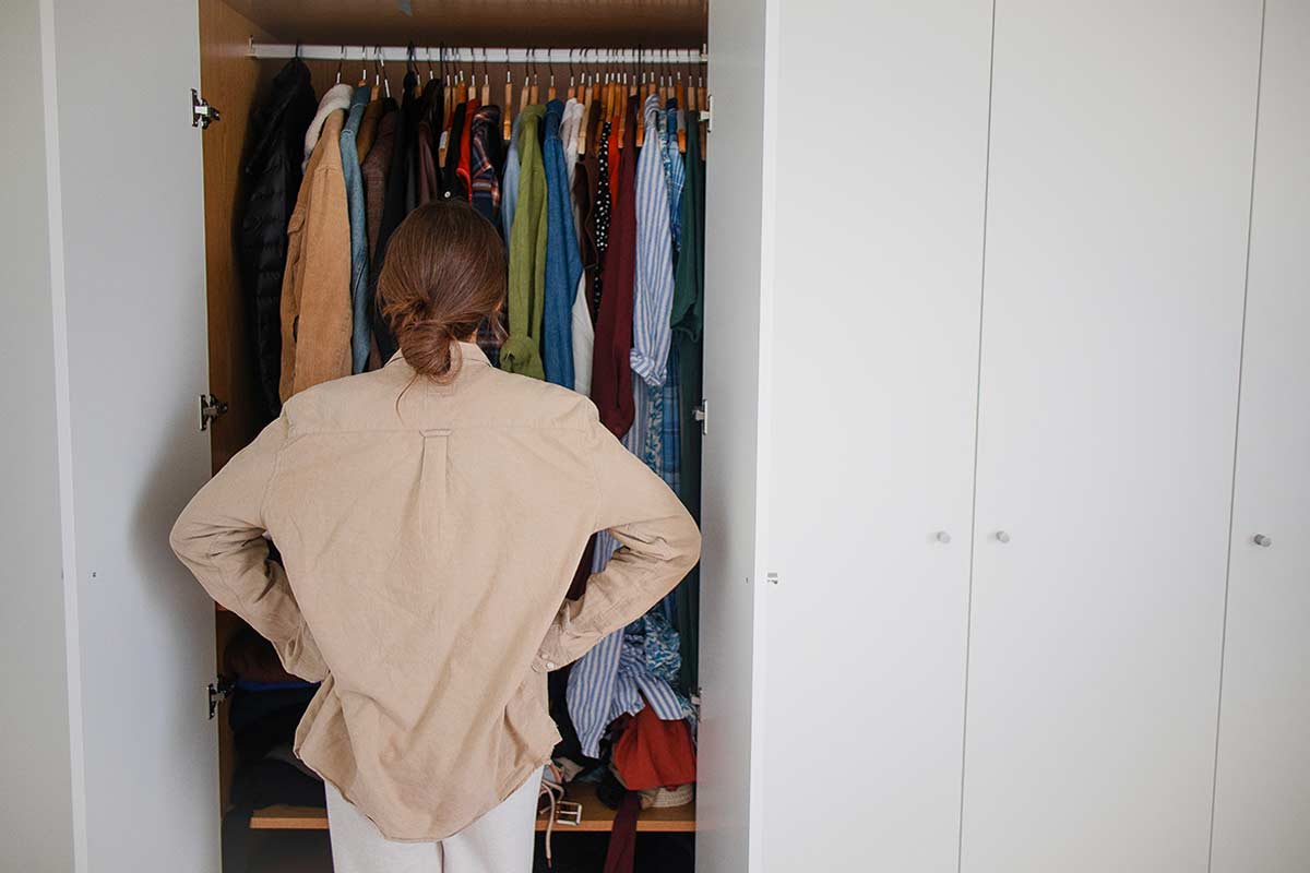Donna di spalle guarda il suo armadio.