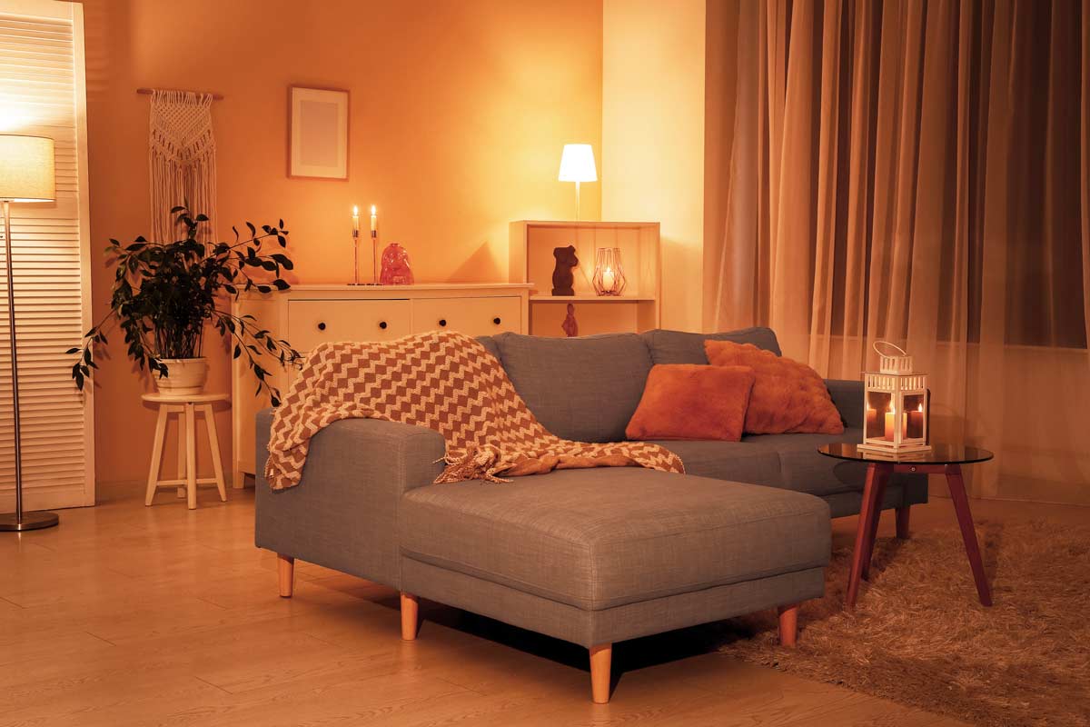 Soggiorno con divano grigio e luci calde d’atmosfera per il relax serale.