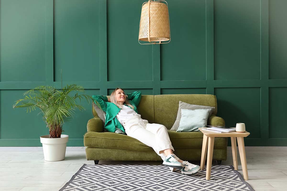 Soggiorno con divano verde oliva e parete verde bosco