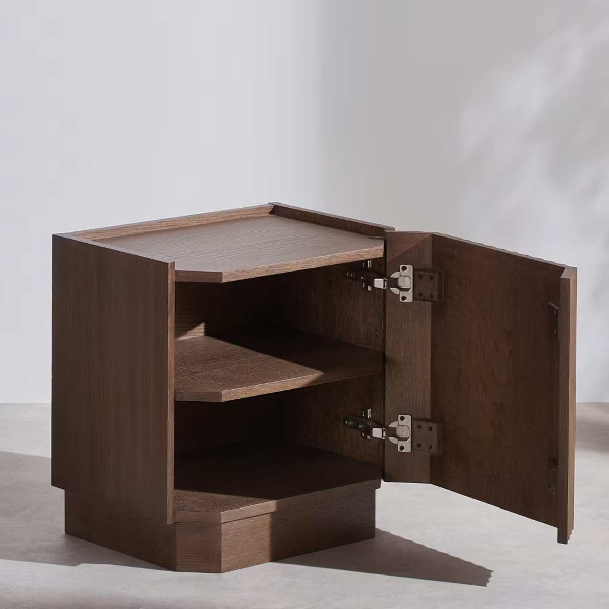 Vista ravvicinata della superficie superiore in rovere tinto del comodino Bosco, con bordo rialzato e scanalature verticali.