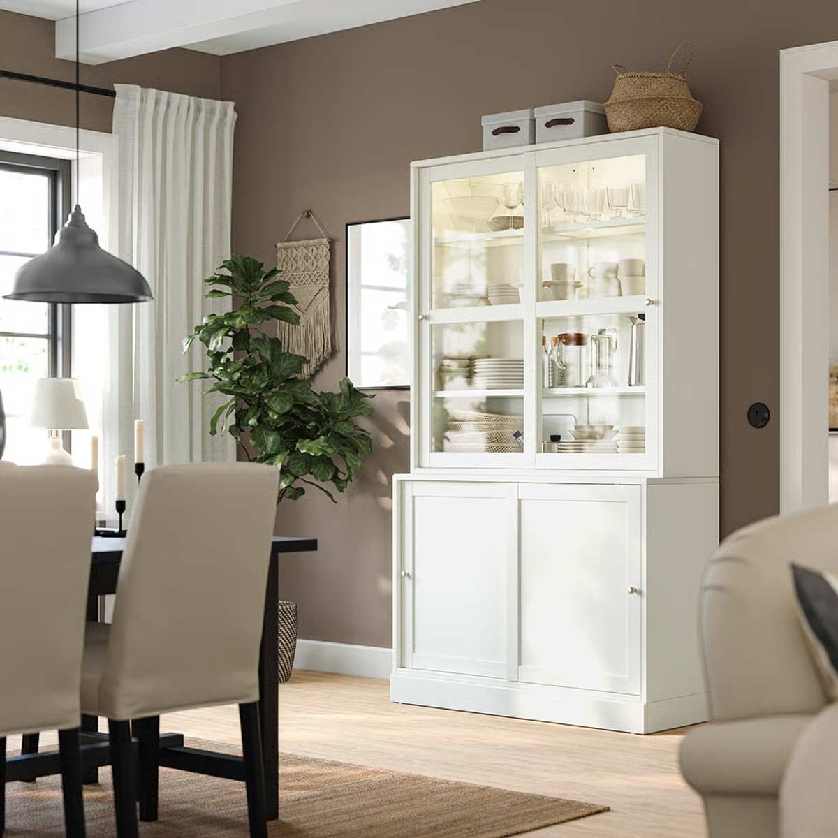 Credenza Havsta IKEA bianca con ante scorrevoli e vetrina espositiva, ambientata in un soggiorno moderno dai toni caldi.