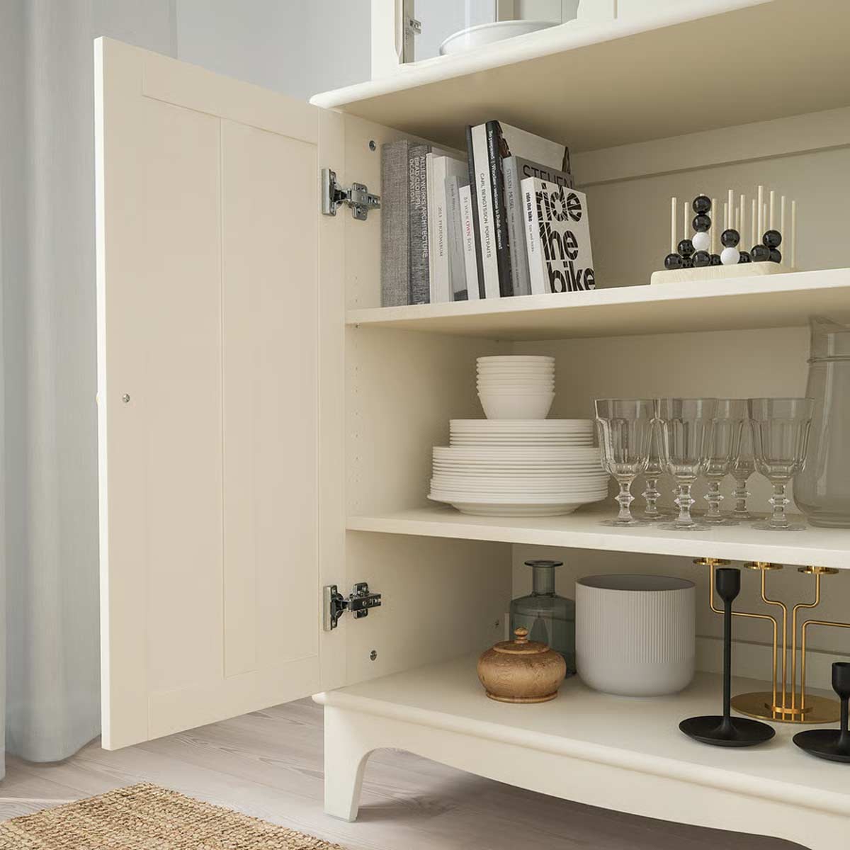 Dettaglio interno credenza Lommarp Ikea: ripiani con piatti, bicchieri, libri e oggetti decorativi in stile minimal.