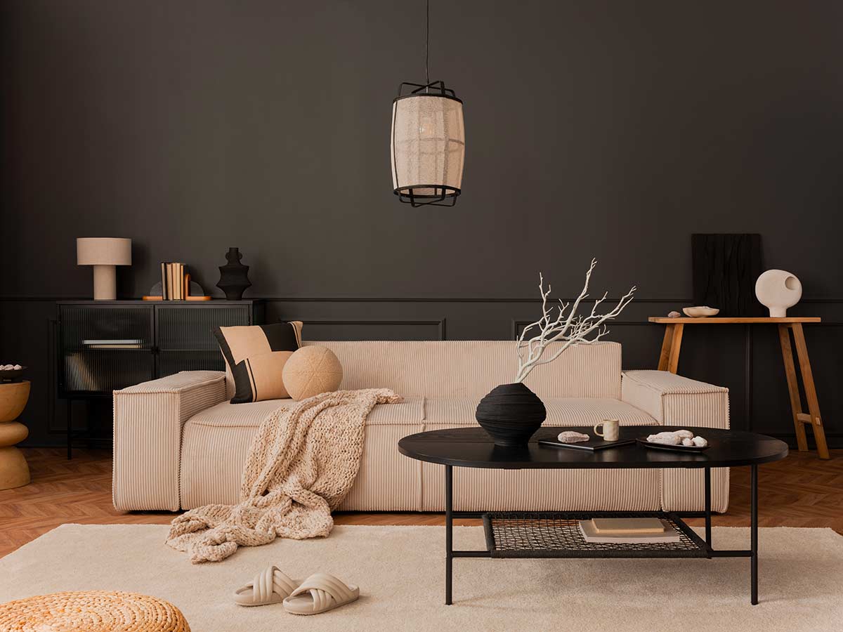Soggiorno moderno con parete nera, divano beige e tavolino scuro, esempio di contrasto elegante tra elementi scuri e arredi neutri.