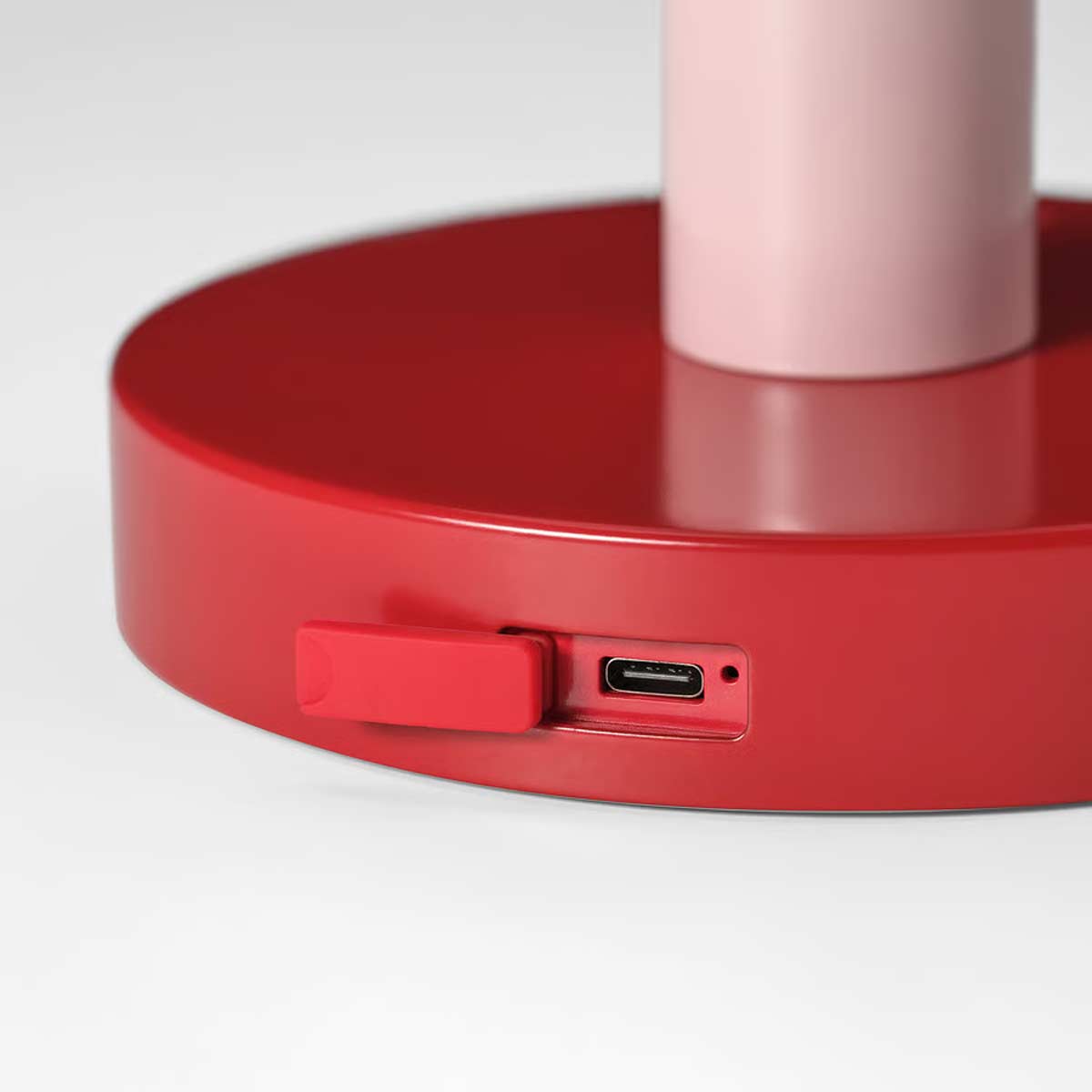 Dettaglio della base rossa della lampada con porta di ricarica USB-C in primo piano.