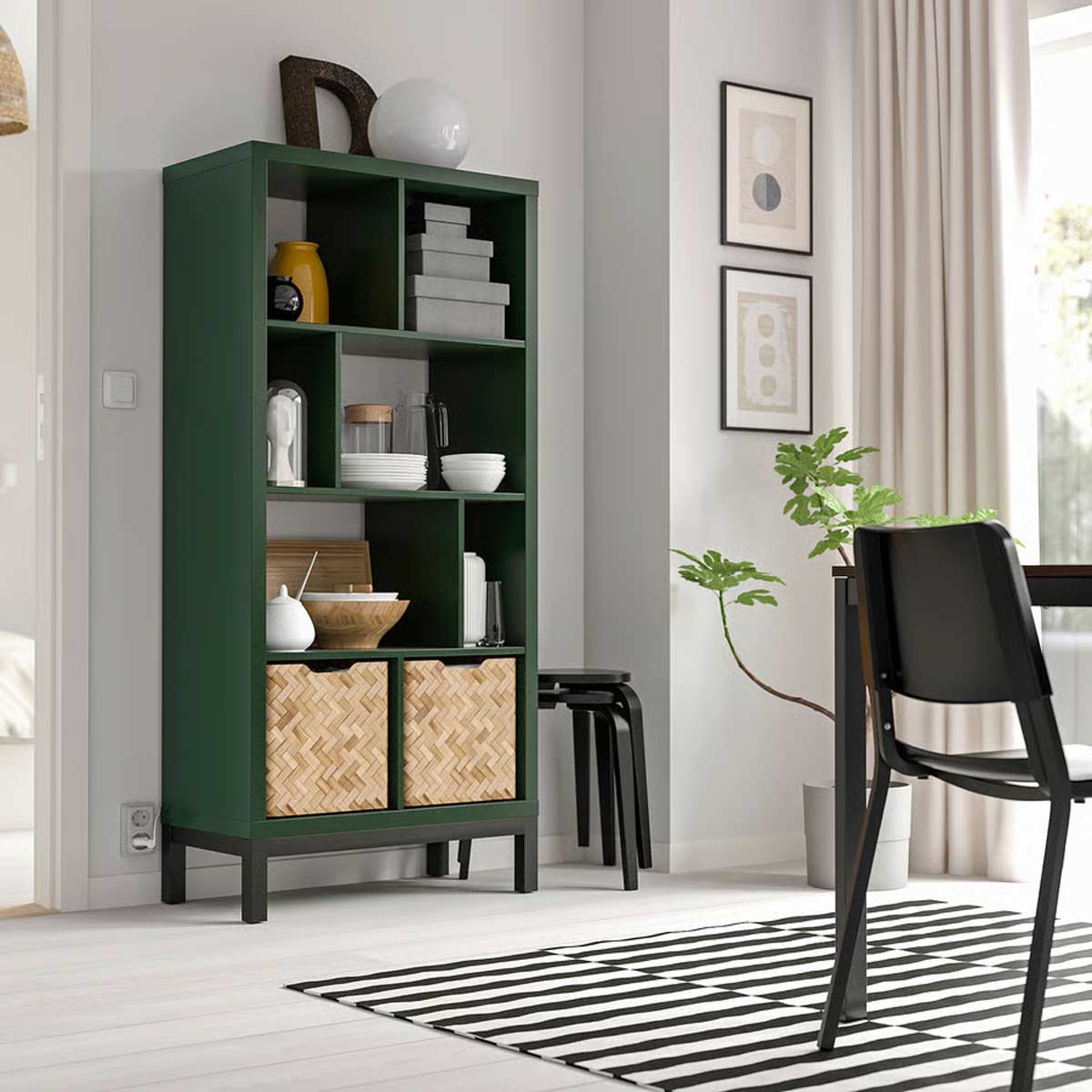 KALLAX verde scuro con base nera in soggiorno, libreria con contenitori intrecciati e oggetti decorativi