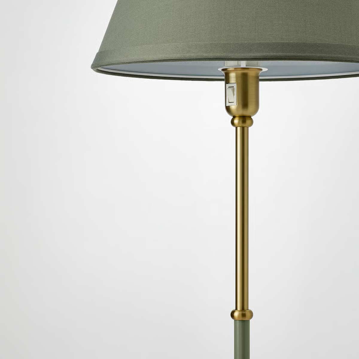 Particolare della lampada da terra IKEA FLYGHÖJD con paralume grigio-verde e dettagli in ottone satinato.
