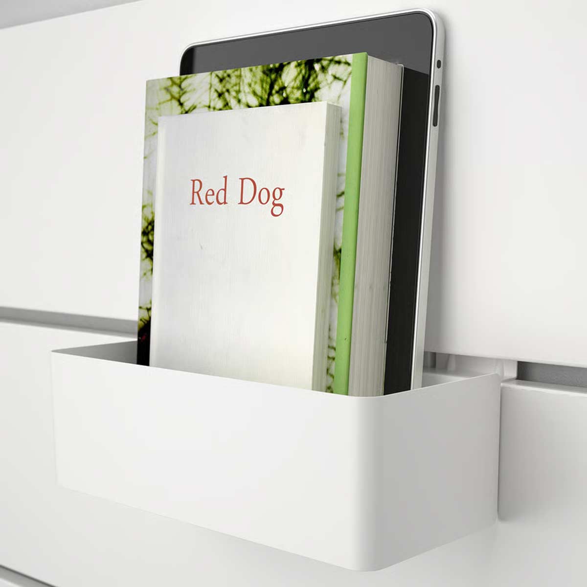 Mensola contenitore bianca fissata alla testiera del letto con libri e tablet appoggiati, soluzione salvaspazio moderna.