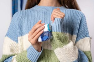 donna rimuove pallini da una maglia di lana