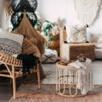 Salotto Boho Chic con poltrona in rattan, tavolino intrecciato, tessili naturali e piante verdi su sfondo luminoso.