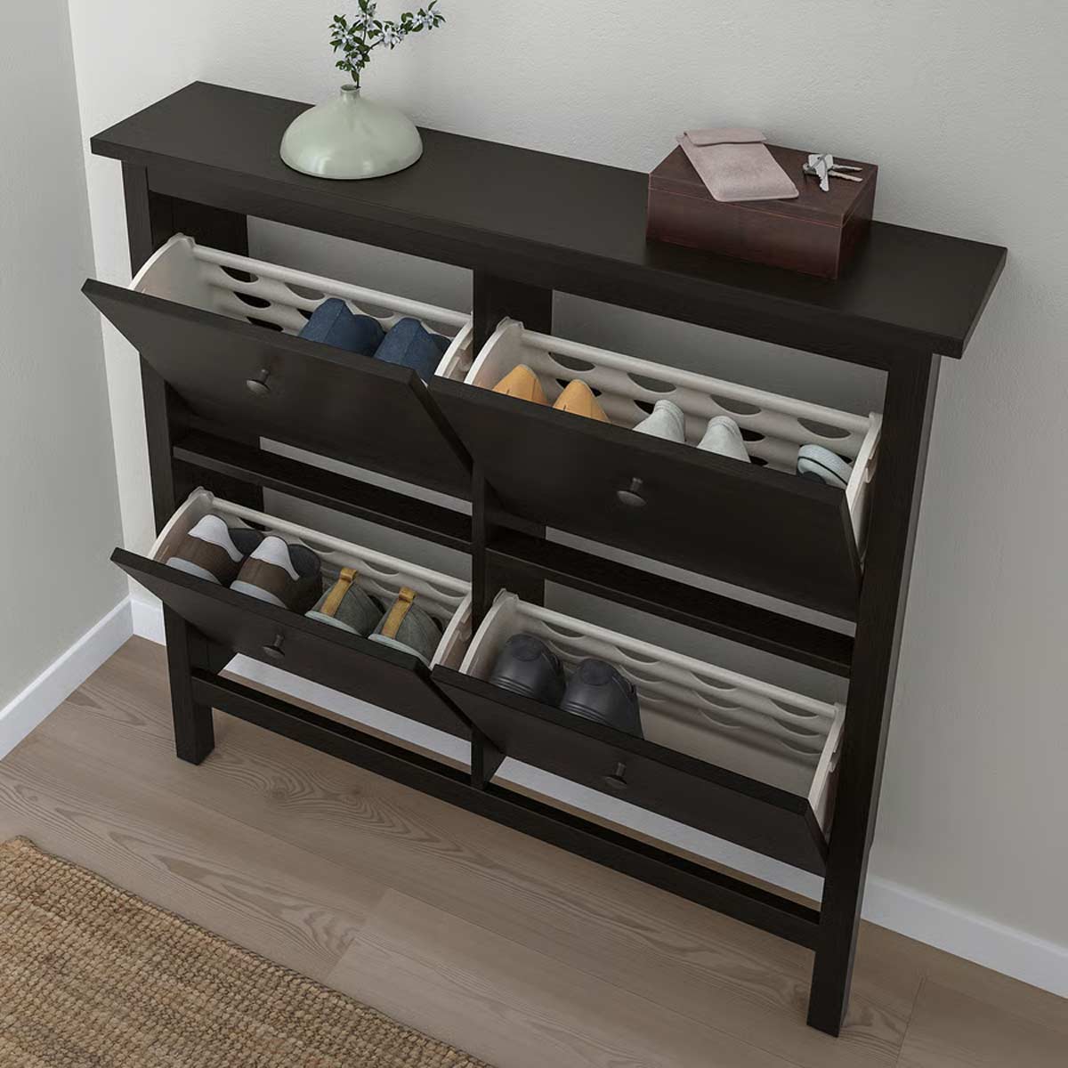 Scarpiera HEMNES marrone-nero IKEA con quattro scomparti aperti, scarpe ordinate e oggetti sul ripiano superiore.