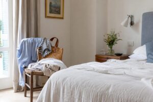 Camera da letto estiva con sedia piena di vestiti vicino al letto