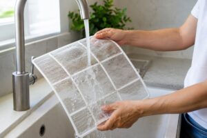 Filtro del condizionatore lavato sotto l’acqua per togliere polvere e odori