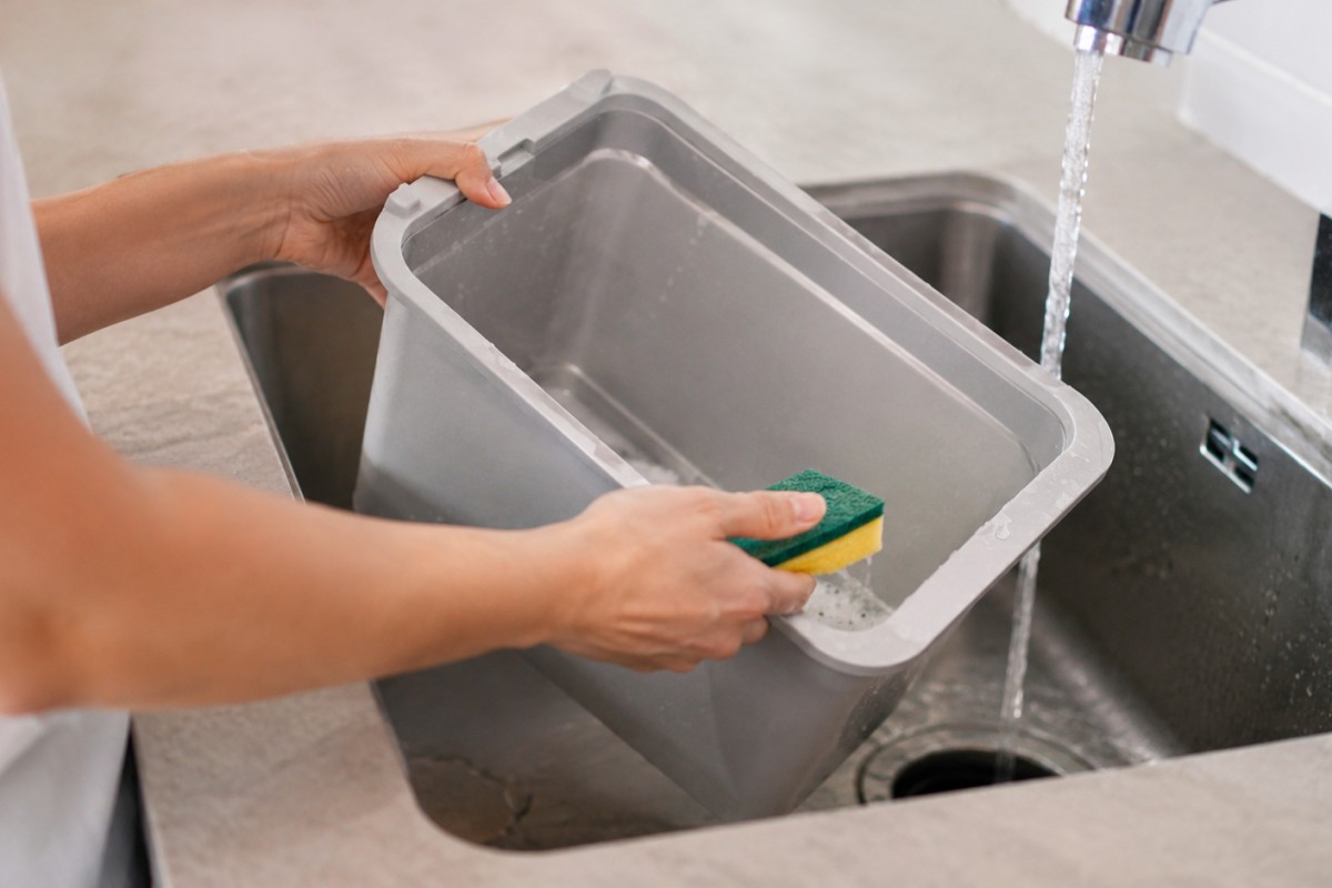 Secchio della pattumiera lavato nel lavello con acqua e sapone delicato